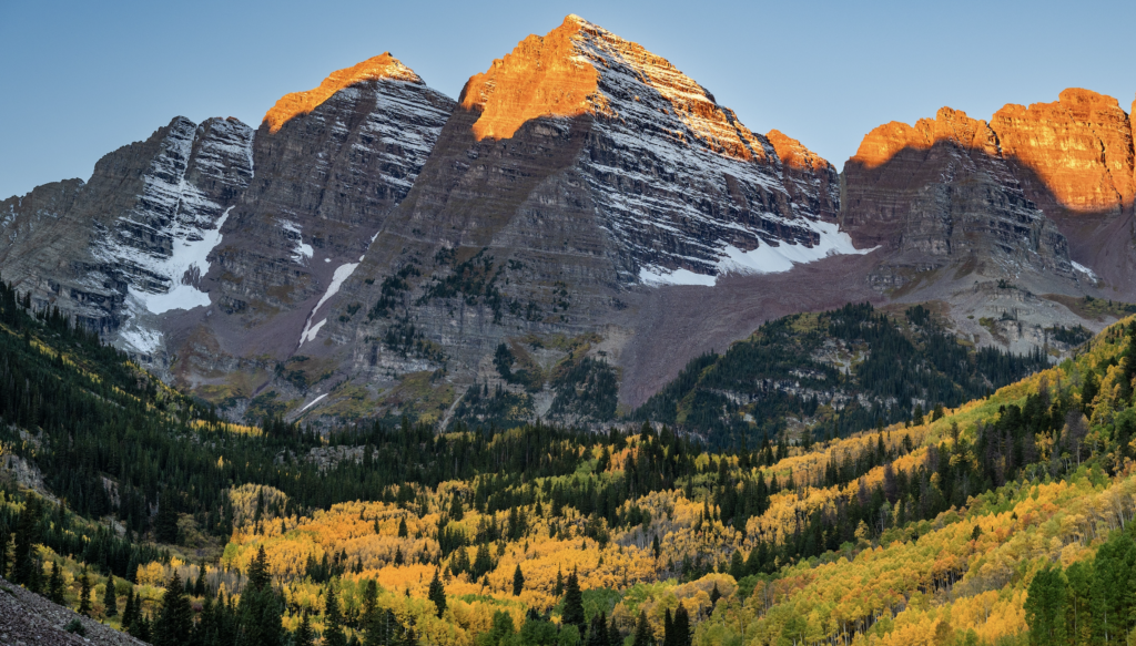 Sunrise over Maroon Bells near Aspen, Colorado, with early morning light touching snow-dusted mountain peaks | Vaquera House